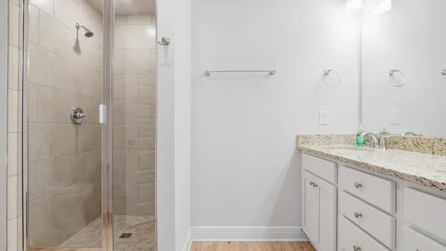 a bathroom with a granite countertop sink a mirror and shower