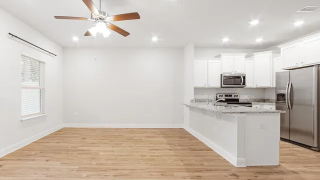 a kitchen with stainless steel appliances a stove top oven a refrigerator cabinets and wooden floor