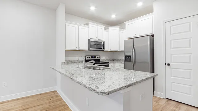 a kitchen with stainless steel appliances granite countertop a refrigerator a stove a sink and a microwave