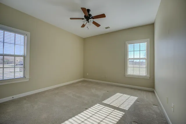 an empty room with windows and ceiling fan