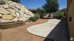 357 East 860 North Hurricane, UT 84737 - Photo 18 of 19 Exterior patio area featuring a curved concrete walkway, a stone retaining wall, and natural rock landscaping