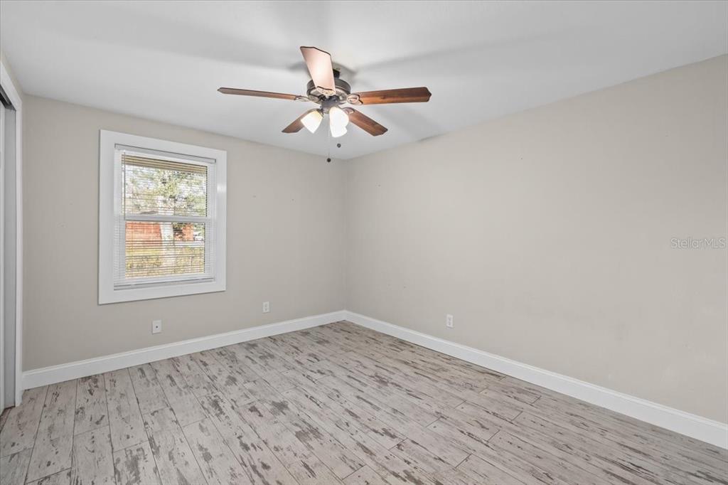 4805 Cooper Road Plant City, FL 33565 - Photo 8 of 45 an empty room with wooden floor fan and windows