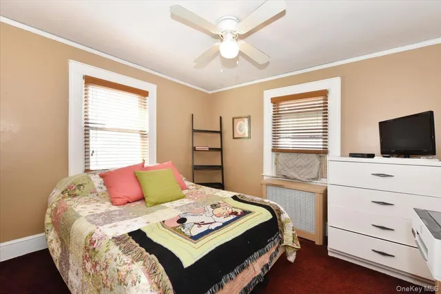 a bedroom with a bed a flat screen tv and a window