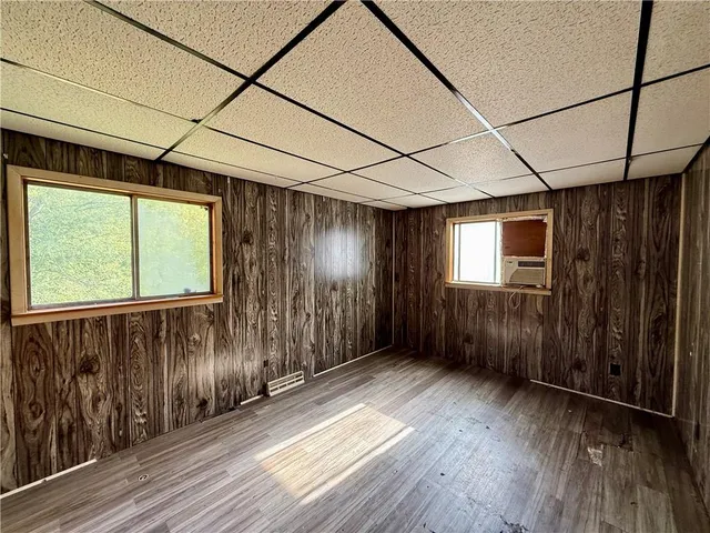 a view of empty room with wooden floor and a window