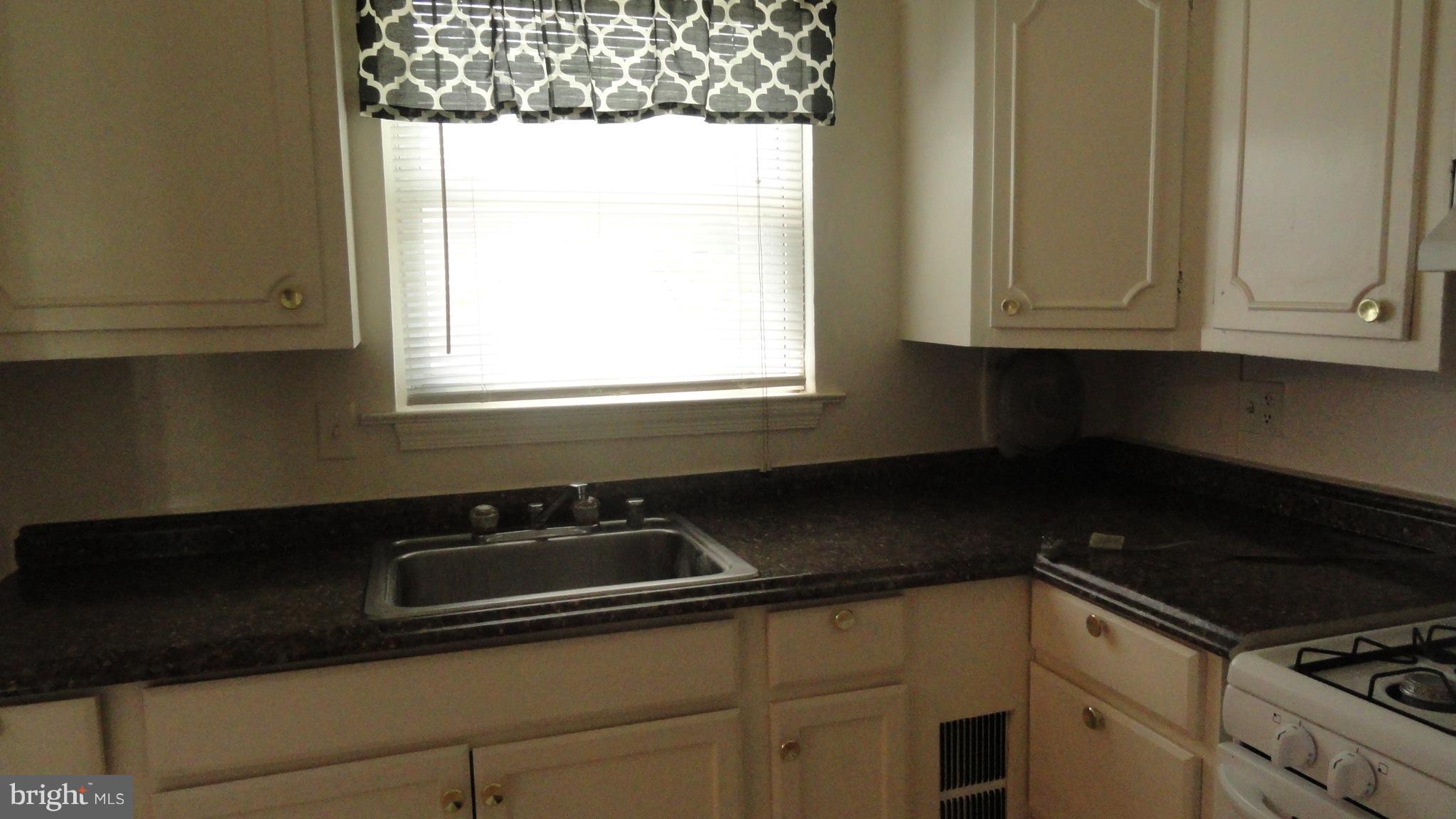 1911 Addison Road South District Heights, MD 20747 - Photo 7 of 15 a kitchen with granite countertop white cabinets and black appliances