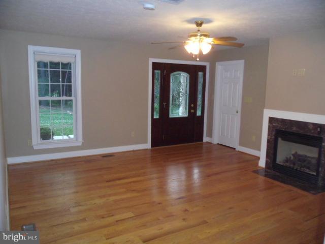 20140 Fort Valley Road Strasburg, VA 22657 - Photo 4 of 25 a view of an empty room with wooden floor fireplace and a window