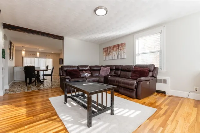 a living room with furniture a wooden floor and next to a window