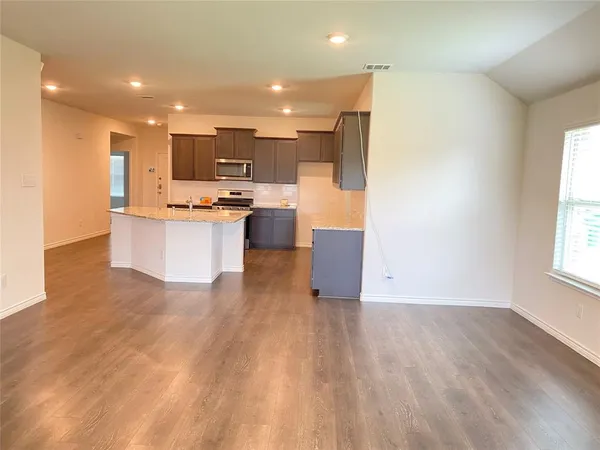 a view of kitchen with kitchen island wooden floors and stainless steel appliances