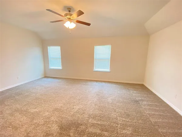 an empty room with a chandelier fan and windows
