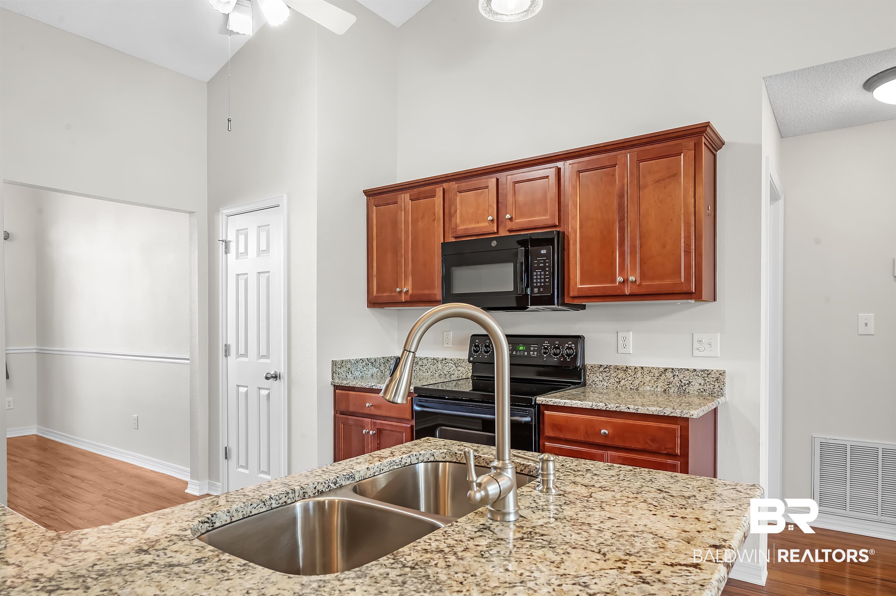 421 Collinwood Loop Foley, AL 36535 - Photo 28 of 62 Kitchen with black appliances, light stone countertops, wood-type flooring, and high vaulted ceiling