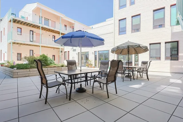 a patio with a dinning table and chairs under an umbrella