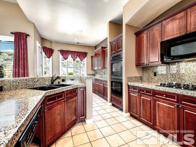 7265 Tempe Court Reno, NV 89511 - Photo 5 of 24 a kitchen with stainless steel appliances granite countertop a stove top oven a sink dishwasher a dining table and chairs with wooden cabinets