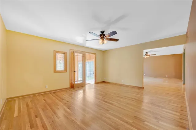 a view of an empty room with window and a ceiling fan