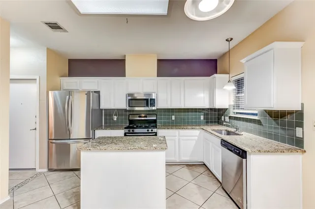 a kitchen with stainless steel appliances granite countertop a sink stove refrigerator and cabinets