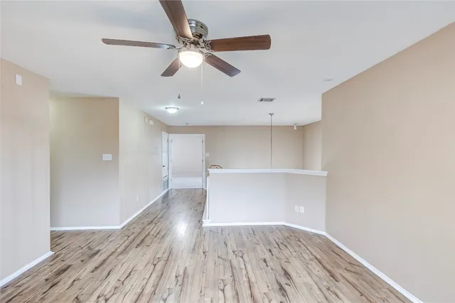 a view of a room with wooden floor and a ceiling fan