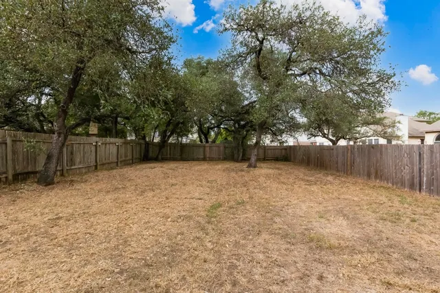 a backyard of a house with large trees and brick walls
