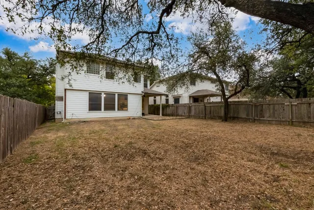 a view of a backyard with large trees and wooden fence