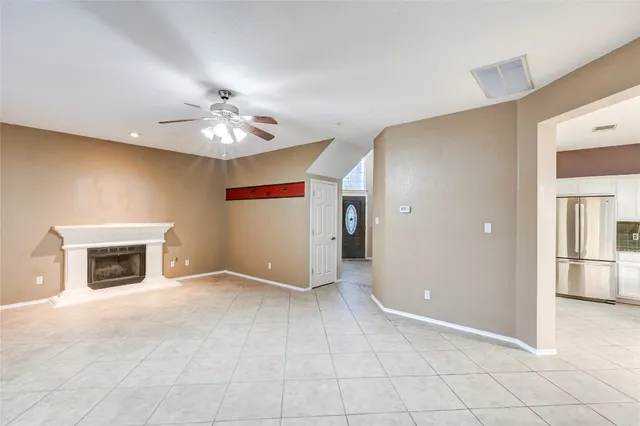 a view of an empty room with a fireplace and a chandelier fan