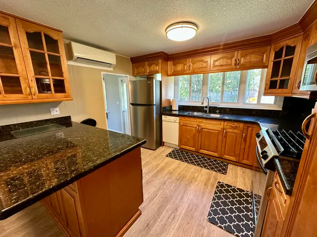 a kitchen with stainless steel appliances granite countertop a refrigerator a stove and wooden cabinets