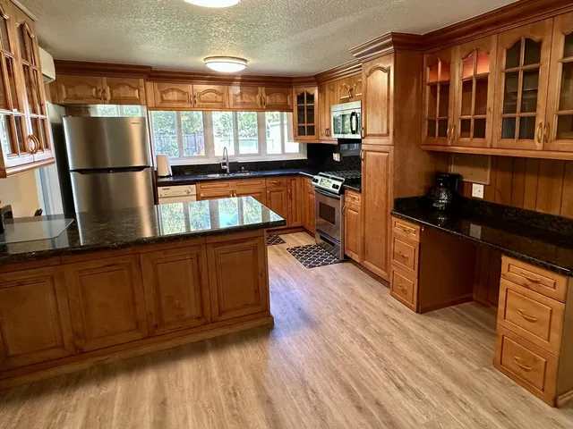 a kitchen with granite countertop wooden floors and black appliances
