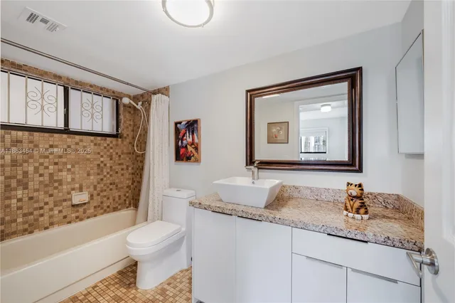 a bathroom with a granite countertop sink mirror vanity and toilet