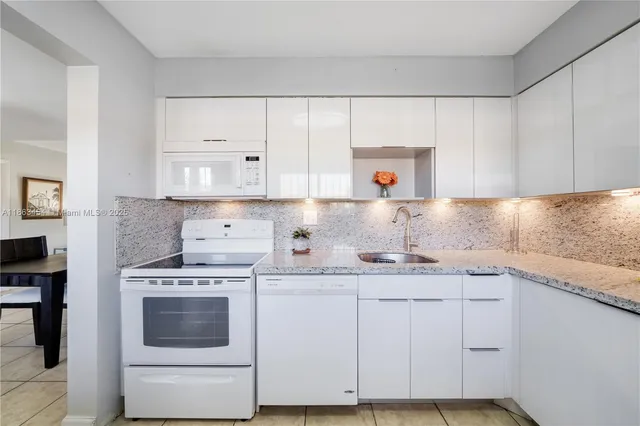 a kitchen with granite countertop white cabinets and white appliances