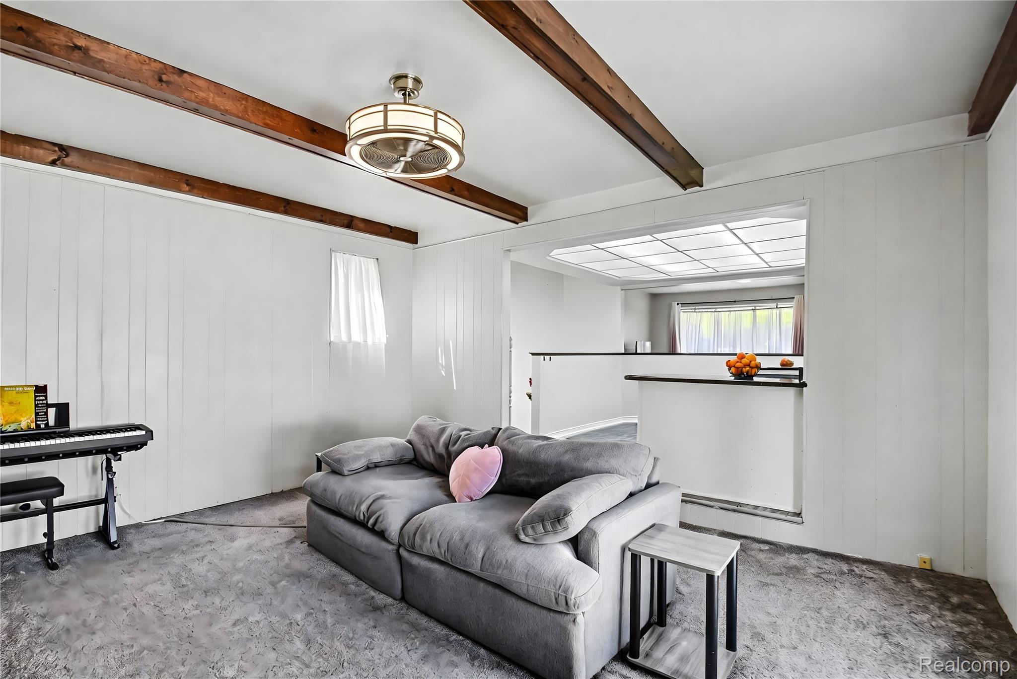 8530 Canal Road Sterling Heights, MI 48314 - Photo 11 of 31 Living area featuring exposed wood ceiling beams, a modern ceiling fan with light, white vertical paneling, and an open pass-through to an additional space with recessed lighting