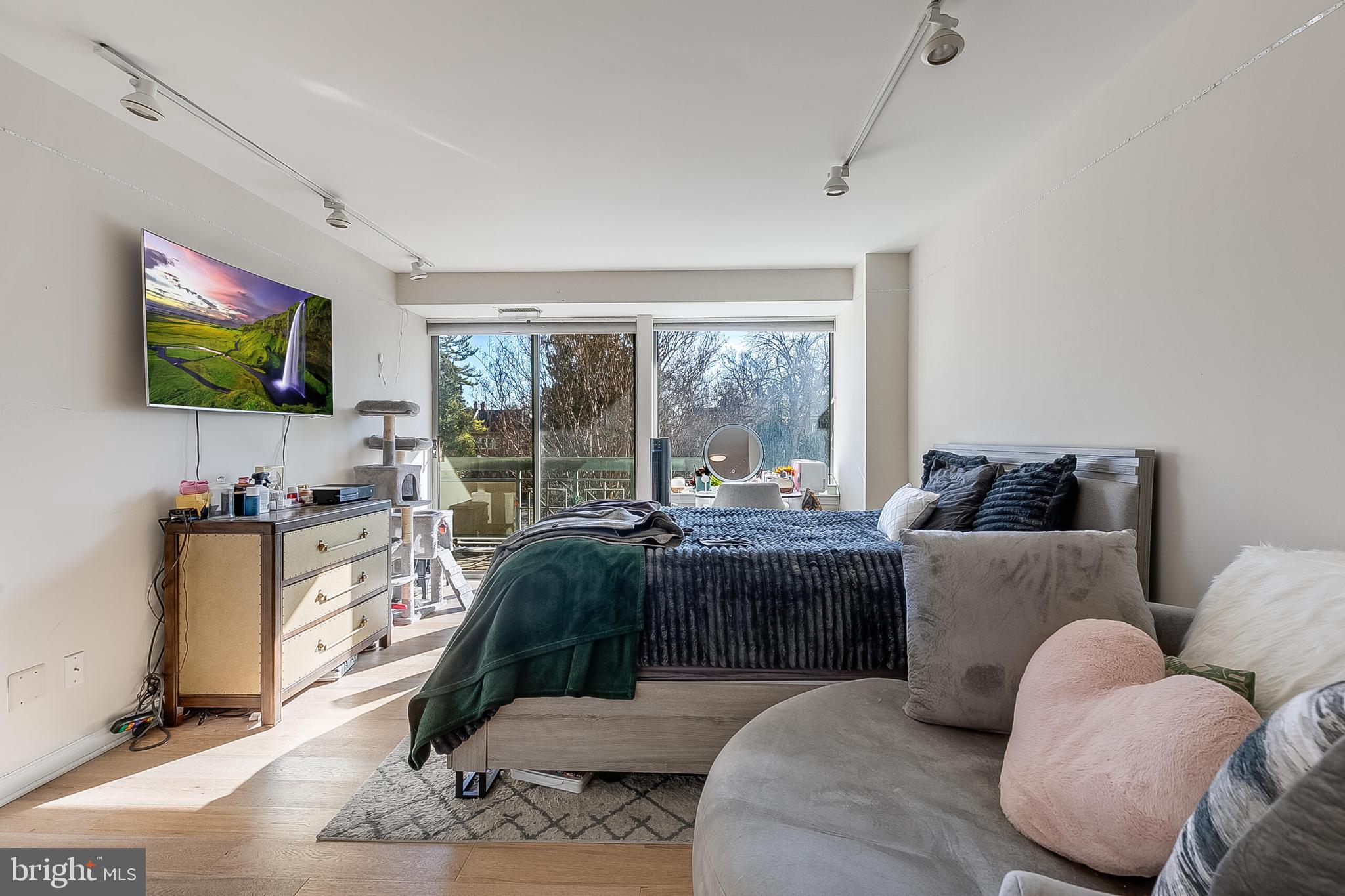 5450 Whitley Park Terrace, Unit 209 Bethesda, MD 20814 - Photo 22 of 29 a living room with furniture a flat screen tv and a floor to ceiling window