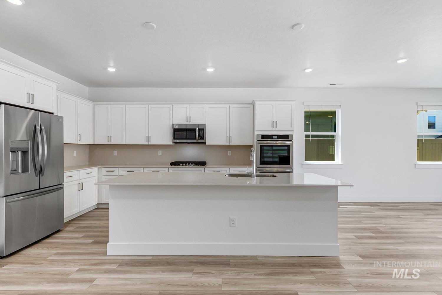 4548 West Wapoot Street Meridian, ID 83646 - Photo 8 of 17 Spacious kitchen featuring white cabinetry, a large central island with a sink, stainless steel appliances, and wood-finish flooring