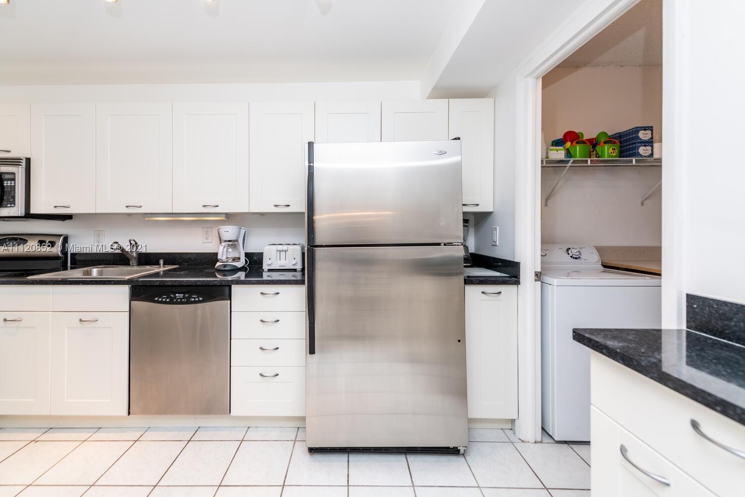 9273 Collins Avenue, Unit 801 Surfside, FL 33154 - Photo 13 of 47 a kitchen with white cabinets and stainless steel appliances