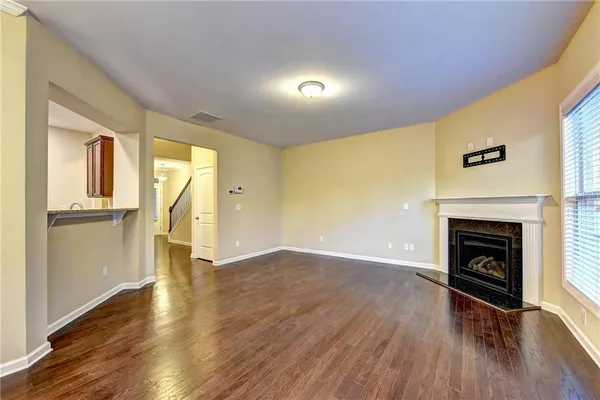 a view of an empty room with wooden floor a fireplace and a window