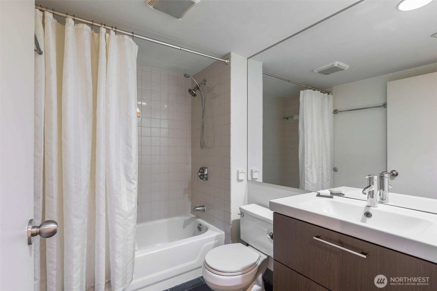 1415 2nd Avenue, Unit 2108 Seattle, WA 98101 - Photo 15 of 27 a bathroom with a bathtub shower sink vanity mirror and toilet
