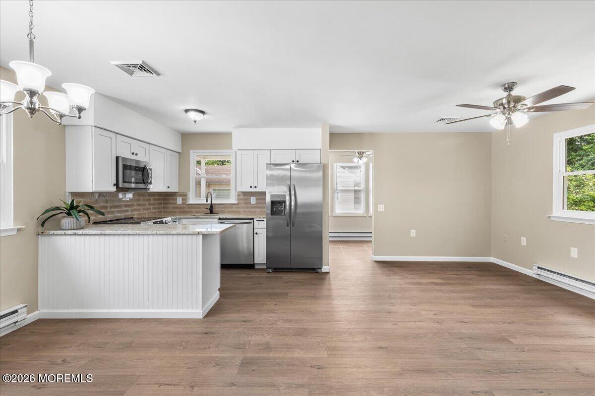 16 D Spring Street, Unit 50 Whiting, NJ 08759 - Photo 7 of 28 a kitchen with granite countertop a refrigerator oven a sink dishwasher and white cabinets with wooden floor