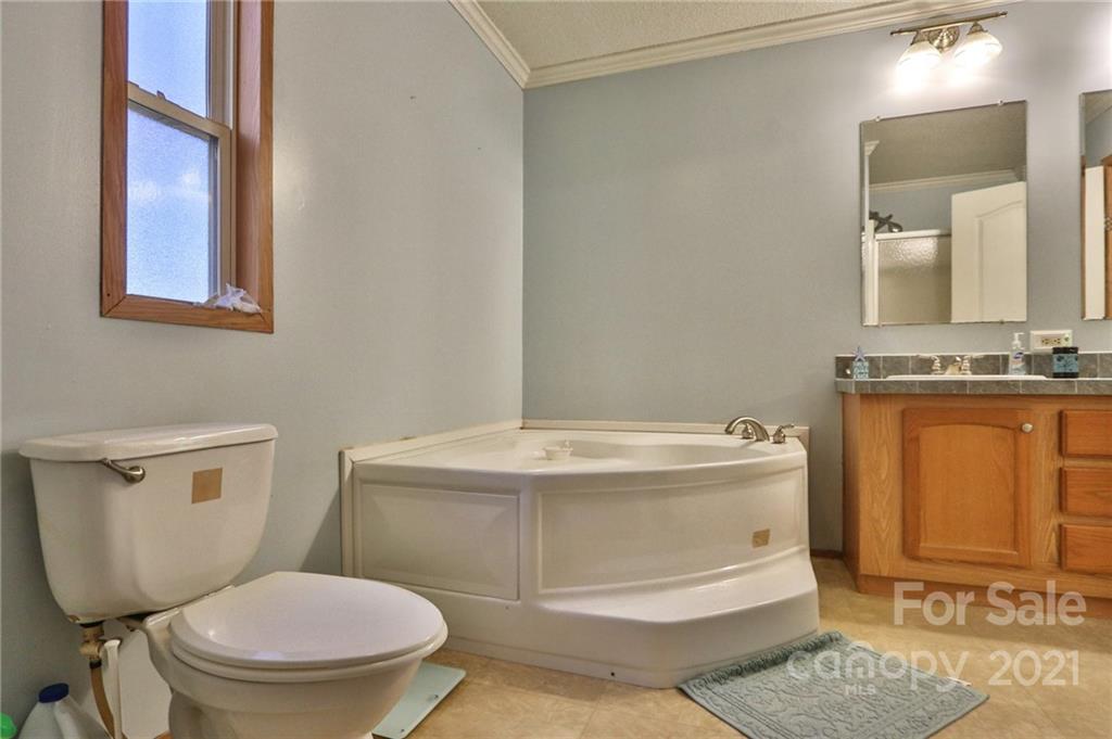 117 Valley Springs Road Olin, NC 28660 - Photo 23 of 38 a bathroom with a granite countertop toilet sink and mirror