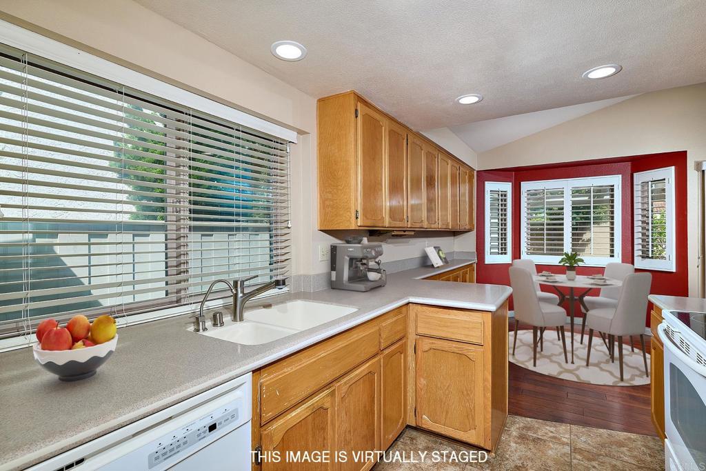 932 Alyssum Road Carlsbad, CA 92011 - Photo 9 of 31 a kitchen with stainless steel appliances wooden cabinets a sink and a large window