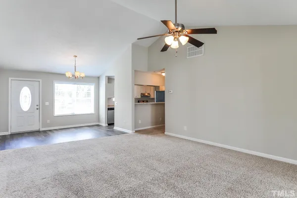 a view of an empty room with wooden floor and window