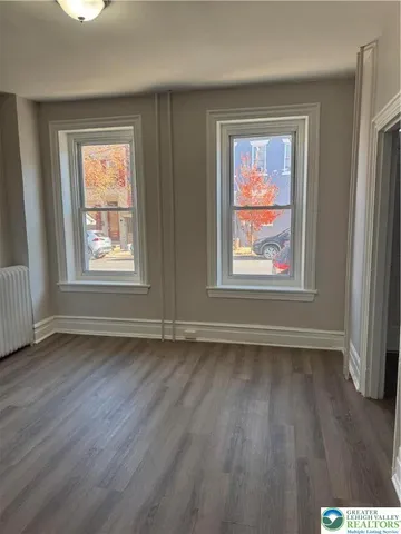 a view of an empty room with wooden floor and window