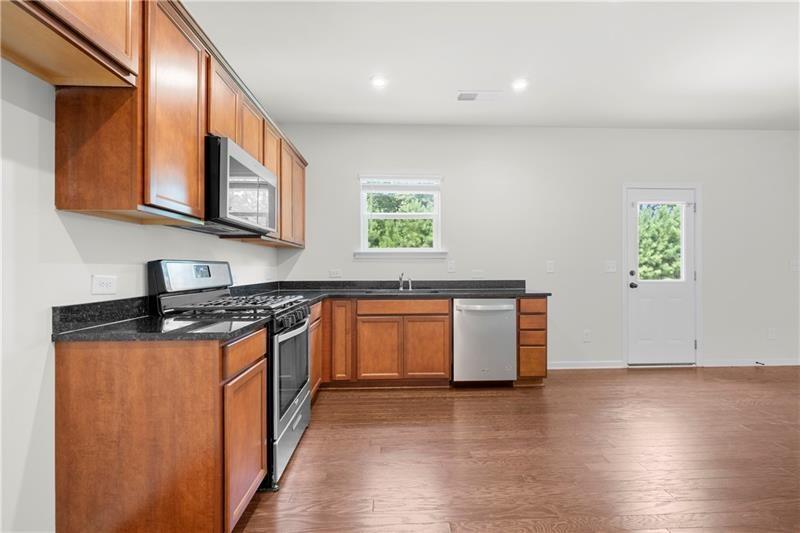5899 Wheeler Ridge Road Auburn, GA 30011 - Photo 22 of 43 a kitchen with stainless steel appliances granite countertop a stove a sink and a microwave