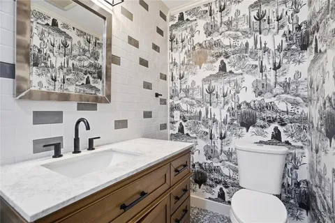 a bathroom with a granite countertop toilet sink and mirror