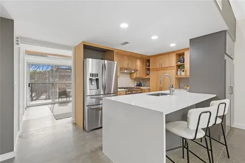 a kitchen with kitchen island a stove a refrigerator a sink and white cabinets with wooden floor