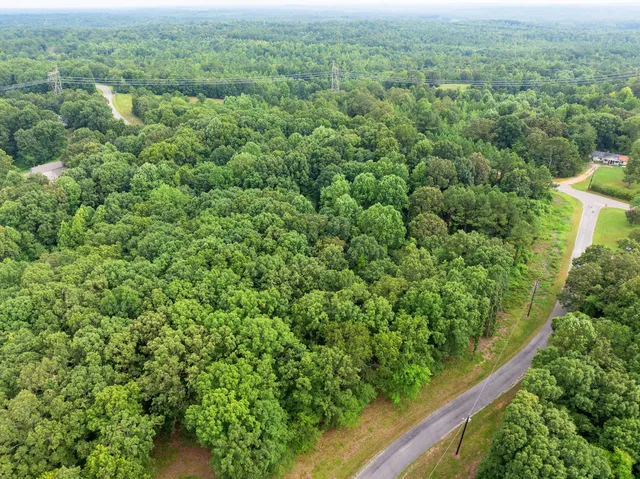 an aerial view of residential house with outdoor space and trees all around