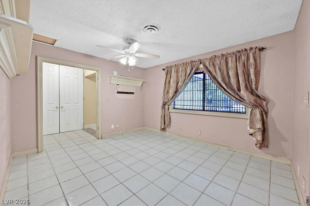 3618 Fieldcrest Road Las Vegas, NV 89121 - Photo 8 of 36 A well-lit sitting area features cool tile flooring, a ceiling fan, and large windows with privacy drapes.