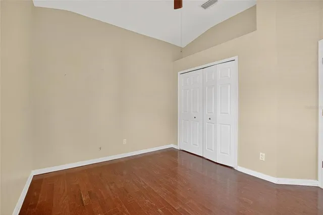 an empty room with wooden floor and ceiling fan