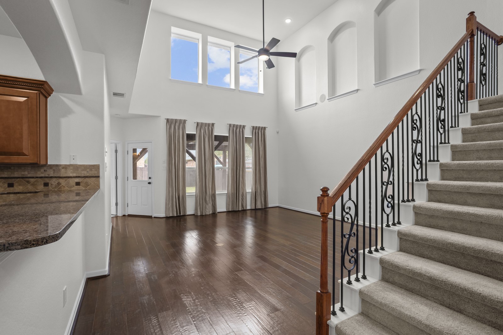 245 Razzmatazz Trail Buda, TX 78610 - Photo 9 of 37 Two-story living area featuring dark wood-finish flooring and a staircase with wrought iron balusters