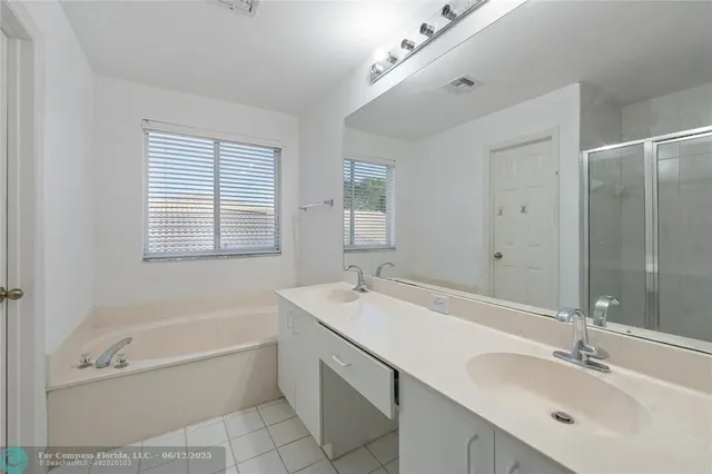 a bathroom with a tub a sink double vanity and a mirror