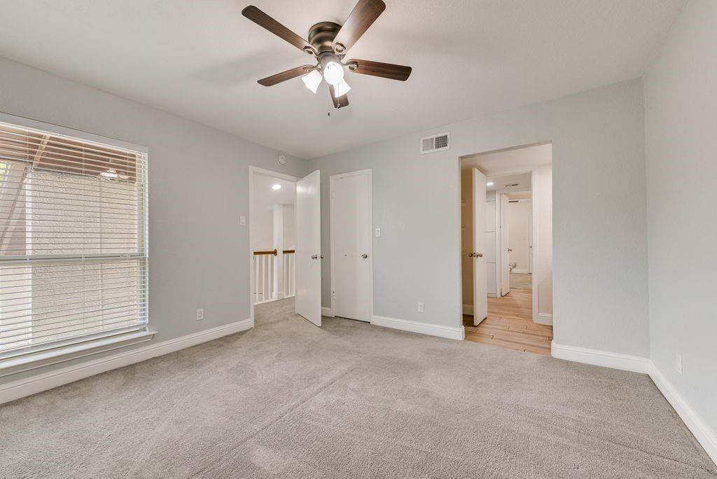 219 West Rochelle Road Irving, TX 75062 - Photo 25 of 29 Carpeted interior space with a ceiling fan, a window with horizontal blinds, and a doorway opening to a hallway with wood-finish flooring