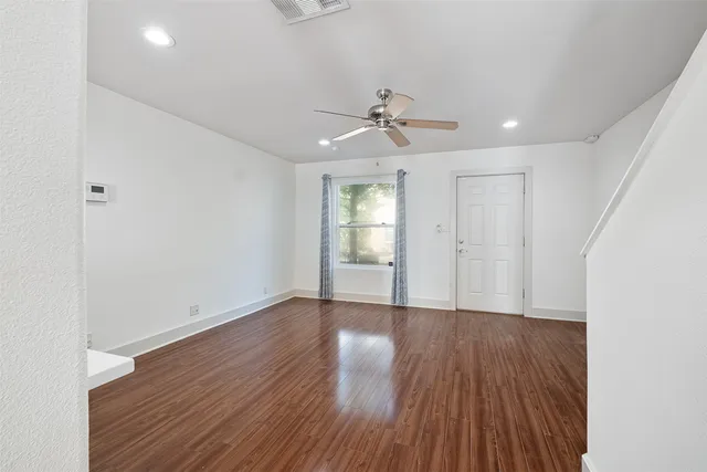 a view of empty room with wooden floor and fan