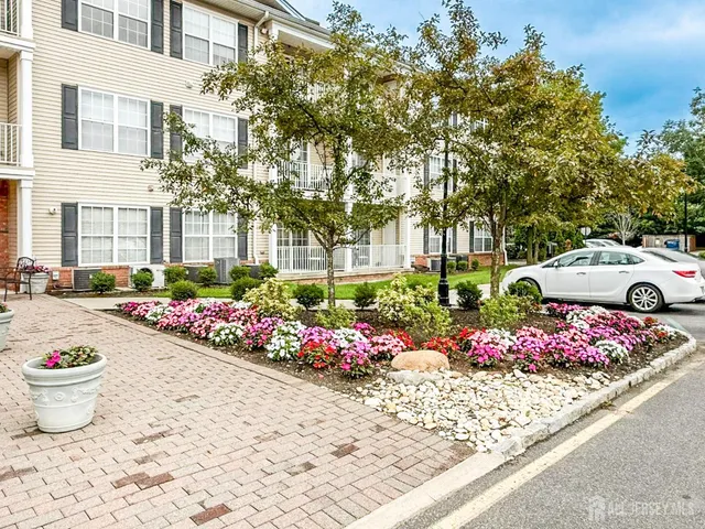 a front view of a house with lots of flowers and trees