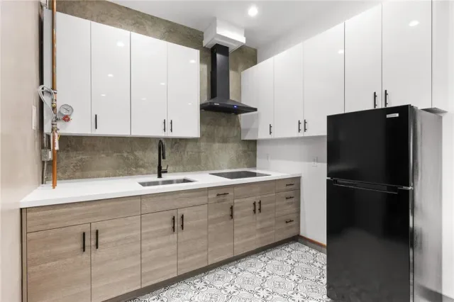 a kitchen with stainless steel appliances granite countertop a refrigerator a sink and white cabinets