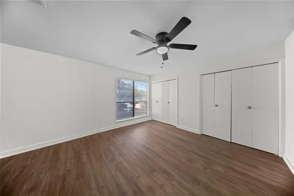a view of empty room with wooden floor and ceiling fan